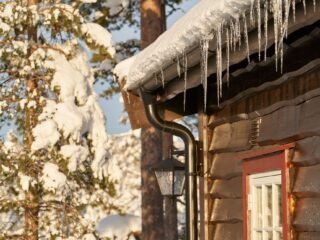 Homeowner cleaning gutters before winter