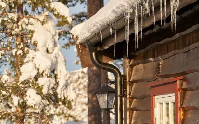 Homeowner cleaning gutters before winter
